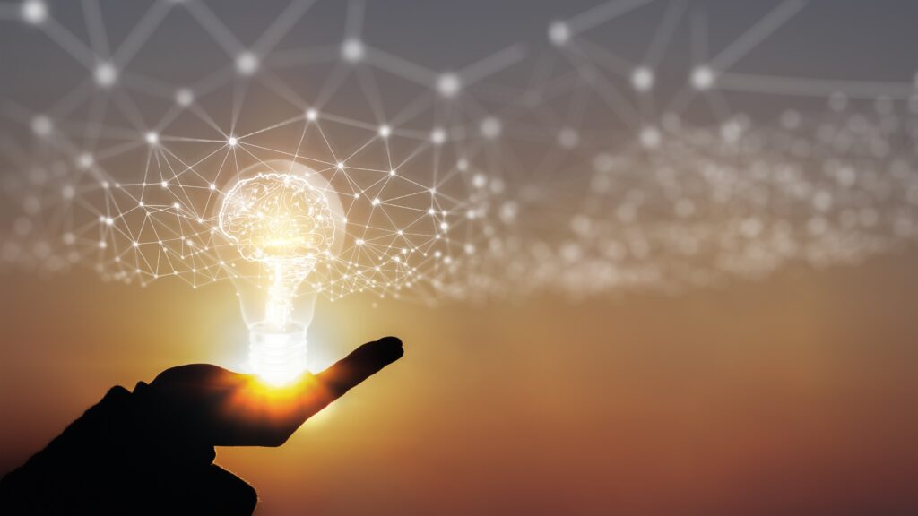A businessman’s hand holds an illuminated light bulb, representing new ideas, innovation, and inspiration concepts.